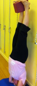 Jody uses a block to learn the lifting action of the legs in head balance.