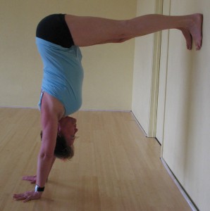 Christie walks up the wall for her handstand, full arm balance, adho mukha vrksasana.